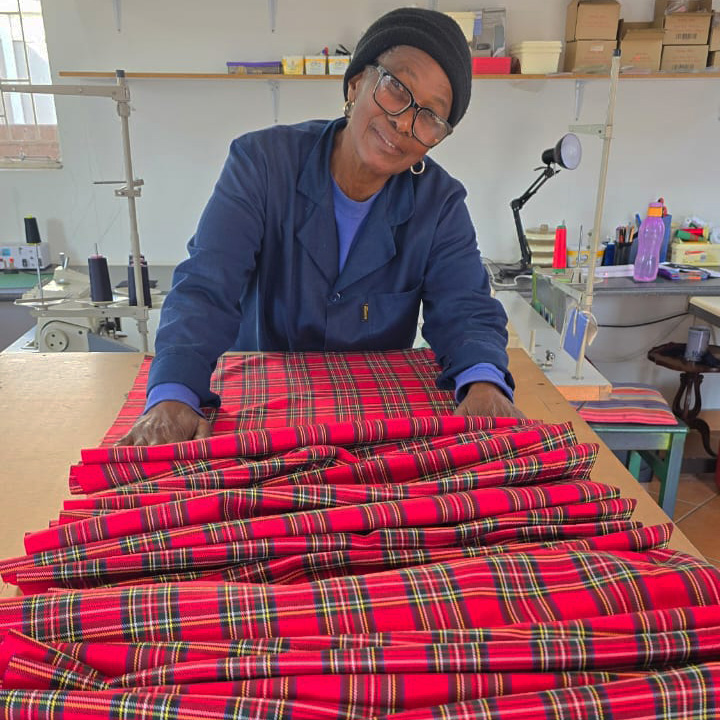 Martha Lekalakala handcrafting a traditional Bakgatla Troop dress from tartan fabric